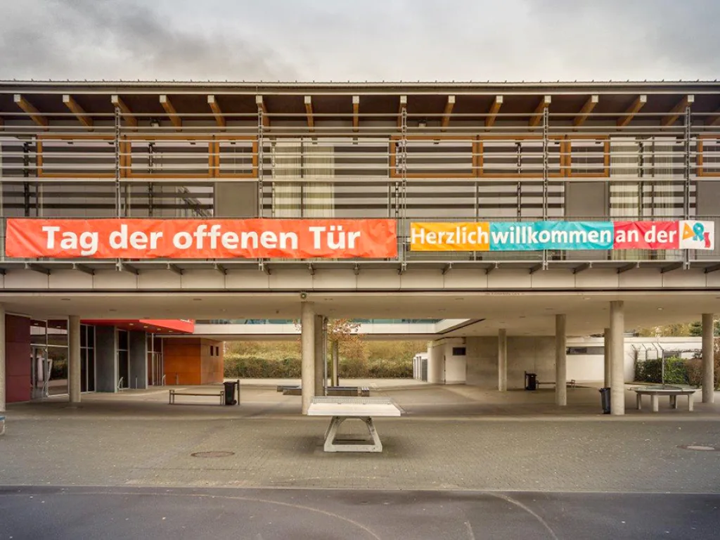 Über dem Schuleingang hängt ein Banner mit der Aufschrift „Tag der offenen Tür“.